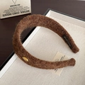 Primer plano de la diadema de lana marrón oscuro con detalle dorado y textura suave - Marrón