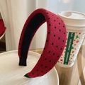 Dettaglio della trama del cerchietto imbottito rosso a pois neri su piatto di ceramica - Stile a Pois