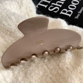 Dettaglio della grande molletta per capelli in acetato marrone moka con scritta dorata - Rosa Antico