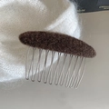 Detailaufnahme eines braunen Wollfilz-Haarkamms mit silbernen Metallzinken auf Strickware - Braun