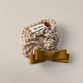 Dettaglio di un elastico per capelli a scacchi gialli con bottone in legno e fiocco - Scrunchie con fiocco a quadretti gialli
