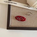 Close-up of a red oval resin hair clip with multi-colored rhinestones on burlap - Oval Shape