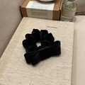 Detailed view of black velvet bow scrunchie on a neutral minimalist background - Black