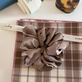 Close-up of brown satin silk scrunchie with elegant pleated texture and soft glossy finish - Brown