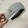 Close-up of light grey polka dot hairband with delicate golden metal bow detail - Gray Bow Headband