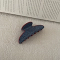 Detailed view of large retro denim blue hair claw clip with red polka dots on an open book - Arc Style