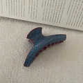 Close-up of denim blue hair claw clip with red polka dots on textured beige background - Hanger Style