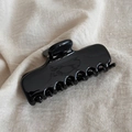 Detail view of large glossy black hair claw clip with mirror finish and curved teeth - Black