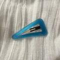 Detail view of triangular sky blue acetate hair clip with France Handmade text on white fabric - Dark Blue