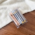 Close-up of pink and grey silk hair scrunchies in a clear box on a wooden surface - Beige Blue Gray