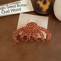 Close-up of tortoise shell pattern large acetate hair claw clip on leather surface - Brown Spotted