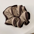 Detailopname van tweekleurige gebreide scrunchie met kaki stof en donkerbruine randen - Bruin