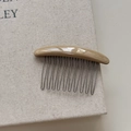 Detail of handmade vintage resin hair comb with engraved logo and silver metal teeth - Khaki