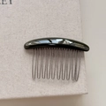Detail of 10-tooth curved hair comb with gold handmade logo and polished black finish - Green