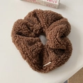 Detailaufnahme eines braunen Plüsch-Haargummis mit dicker Fleece-Struktur auf dem Tisch - Kaffee