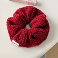 Detailansicht von burgunderrotem Sherpa-Haargummi mit handgemachtem Etikett - Rotes Plüsch-Scrunchie
