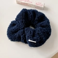 Detail eines dunkelblauen Plüsch-Haargummis mit Teddy-Vlies-Textur und Webetikett - Marineblau Haargummi