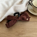 Detail of dark brown velvet bow hair claw clip with golden heart charm on wooden desk - Caramel color