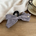 Close-up of a large grey velvet bow hair claw with a gold heart detail on a knit background - Gray