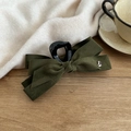 Detailed view of large dark green velvet bow hair claw with a heart-shaped silver charm - Green