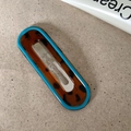 Close-up of oval tortoiseshell hair clip with a bright blue border and metal BB clip - Hollow Oval