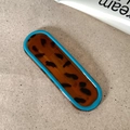 Detail of tortoise shell hair clip with vibrant sky blue border on textured background - Solid Oval