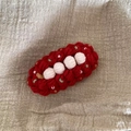 Détail d'une pince à cheveux au crochet rouge avec pompons blancs et perles de nacre - Rouge