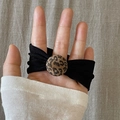 Dettaglio dell'elastico per capelli nero con perla leopardata indossato sulla mano - Nero