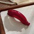 Dettaglio di un fermaglio a banana rosso intenso lucido con denti antiscivolo interni - Rame Retrò