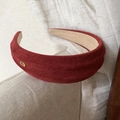 Detail of burgundy faux suede headband featuring a gold-toned handmade metal tag - Red