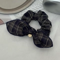 Detailed shot of a vintage plaid hair scrunchie with a bow and gold pendant on fabric - Blue and Green Plaid