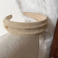 Detail of khaki faux suede wide headband with a golden oval metal emblem attachment - Khaki