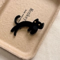Détail d'une pince à cheveux chat noir minimaliste avec yeux dorés et finition lisse - Noir