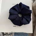 Detalle de un coletero de tela vaquera azul marino plisado sobre un libro - Azul