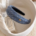 Détail de la texture d'un serre-tête en laine à rayures avec étiquette dorée - Bleu