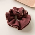 Detailed view of dark reddish-brown knit scrunchie with light gold wavy embroidery - Brown