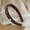 Close-up of vintage brown plaid headband with a circular gold metal logo detail - Coffee Plaid
