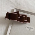 Detail of dark brown wool bow banana hair clip with light pink edging on a tray - Mocha Cocoa