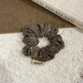 Close-up of a brown knitted scrunchie with a logo label on soft wool texture - Brown Hair Ring