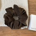 Macro detail van bruine chenille scrunchie met FMdrea-merklabel op witte gebreide ondergrond - Donkere Koffie