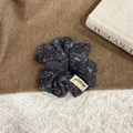 Detailed close-up of dark charcoal tweed knit scrunchie with a stylish side fabric label - Black Hair Tie