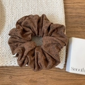 Detail van een bruine bloemen scrunchie op een gebreide mat en houten ondergrond - Bruine Bloem