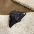 Macro shot of a dark gray knit hair clip with a gold metal label and warm cozy background - Black Claw Clip