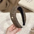 Detailed close-up of brown knitted headband with golden metallic tag and thick texture - Wide Headband / Brown