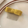 Détail d'un peigne à cheveux avec nœud en tricot jaune, texture pelucheuse et dents en métal - Jaune