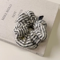 Nahaufnahme von Strick-Scrunchie mit schwarz-weißen Streifen und goldenem Knopf-Detail - Off-White Haargummi
