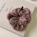Detail eines rosa Strick-Haargummis mit Tweed-Struktur und goldenem Anhänger - Rosa