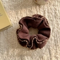 Detail of dark brown knitted scrunchie with beige wavy edges on soft plush background - Brown