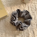 Detail of grey knitted hair scrunchie with blue scalloped edges on soft fleece texture - Gray