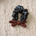 Dettaglio di un elastico per capelli a scacchi con fiocco di velluto su sfondo morbido - Elastico con fiocco
